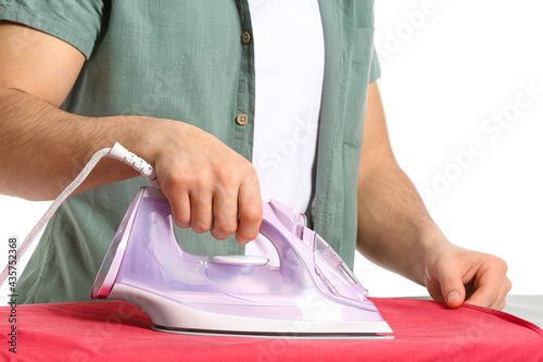 Young man ironing clothes on white background, closeup