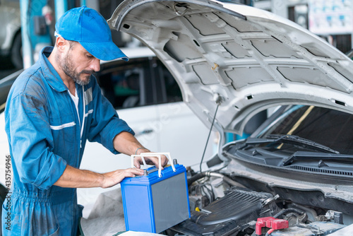 Car repairs. Auto services and Small business concepts. A car mechanic is replacing the battery in an auto repair center. photo