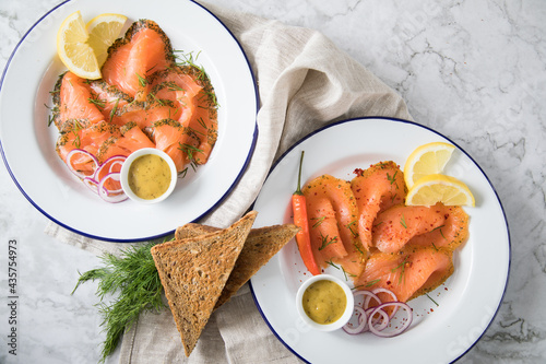 Gravlax Graved Lachs Asiaitsche Art und Klassisch, ein roh gebeizter Fisch mit Zitronengras, Chili, Dill, Hovmästarsås Senf Soße, Toast, Zwiebel Ringe und Zitrone auf Emaille Teller und Leinen Tuch au photo