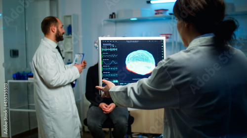 Science doctor looking at computer with medical brain scan film showing on monitor in neurology clinic. Woman sitting in neurological scientific laboratory treating nervous system dysfunctions