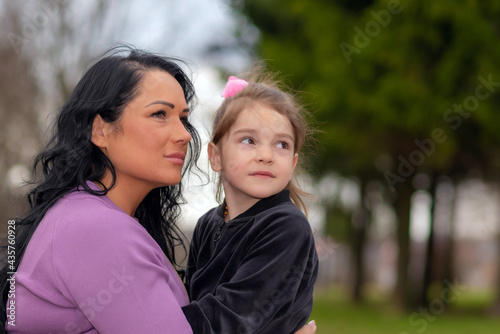 Cute 5 years old girl and her mom sit on a park bench in summer.Family and lifestyle concept.Closeup.