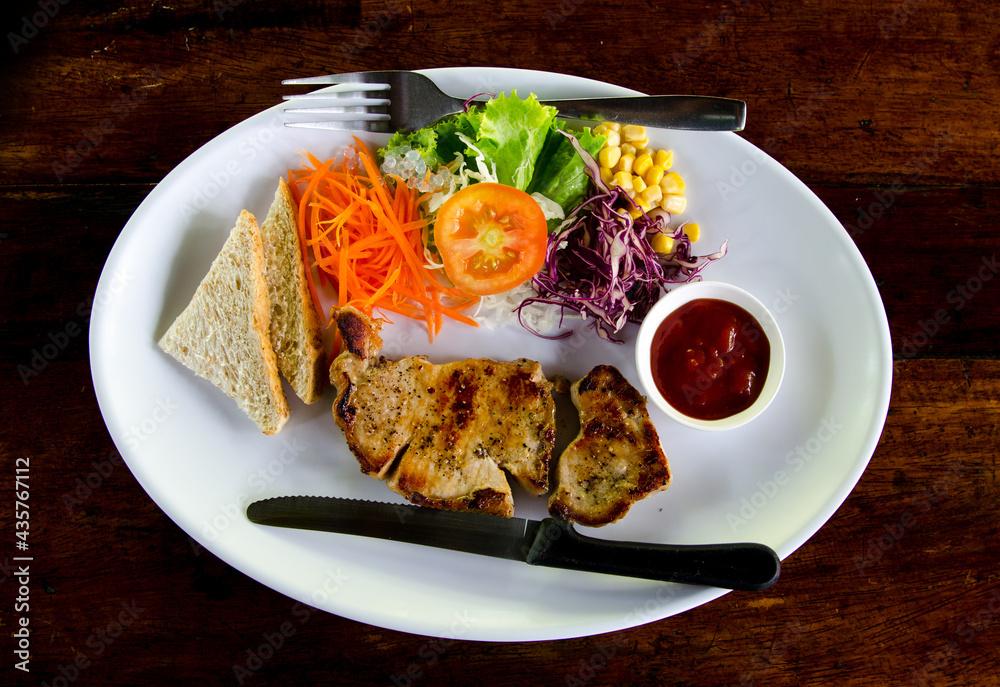 plate of grilled pork with french fries and salad on dark background plate of grilled pork with french fries and salad on dark background