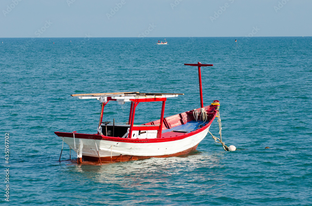 Small red boat in the water close to the beach