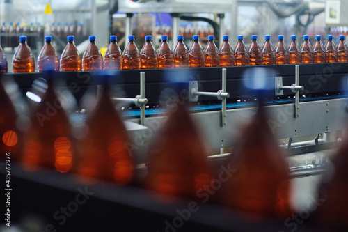 Plastic beer bottles on a conveyor belt in the background of a brewery