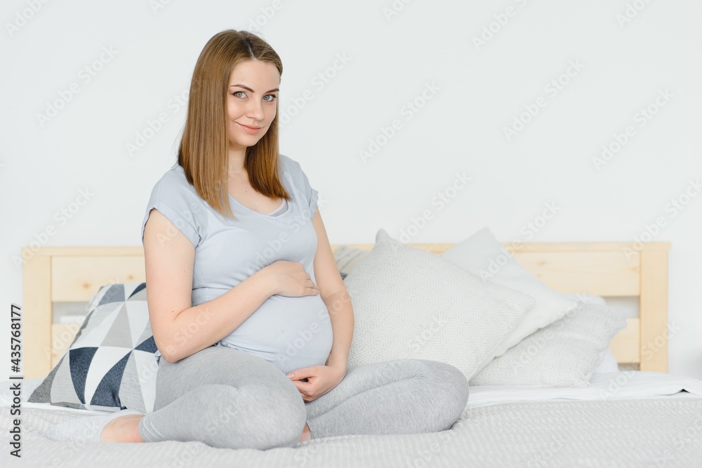 Young pregnant woman sitting on sofa Young pregnant woman sitting on sofa