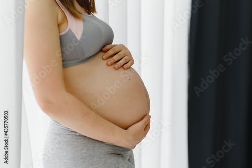Free Download Young pregnant woman holds her hands on her swollen belly. Love concept. Horizontal with copy space - GFXLoad