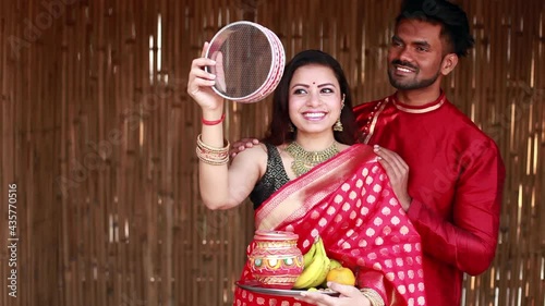 Indian woman celebrating Karva Chauth by looking at her husband after looking at the moon at night