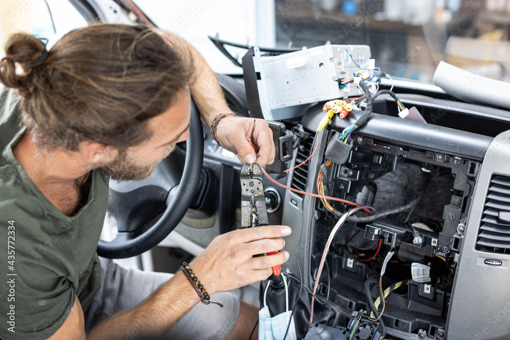 Man working on electronics inside the center console of a car Man working on electronics inside the center console of a car