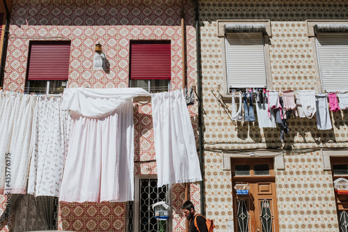 A young traveler walking on a traditional street with 
clothes hanging and old tiled walls in Afurada, Porto