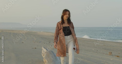 Giovane bella ragazza con stivali neri balla in spiaggia vicino al mare photo