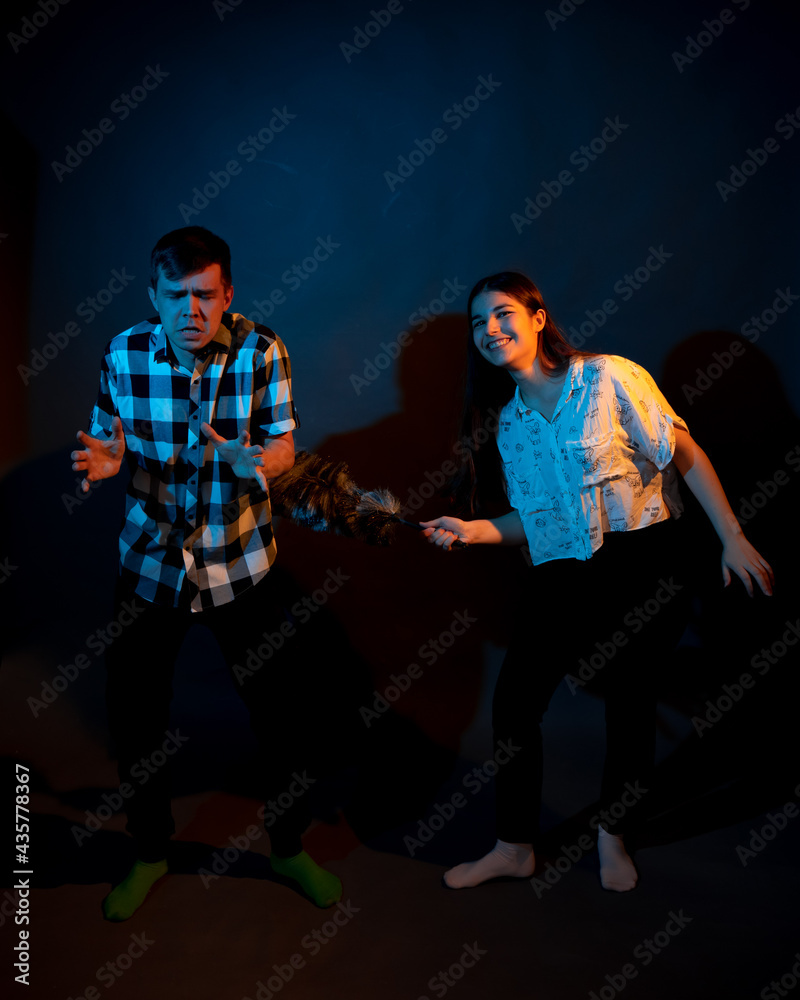 Fototapeta premium A guy in a plaid shirt and a girl with a dust brush against a dark background