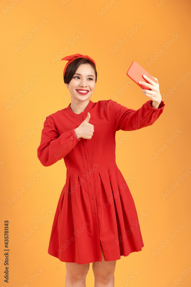Portrait of a pretty girl taking a selfie isolated over yellow background Portrait of a pretty girl taking a selfie isolated over yellow background