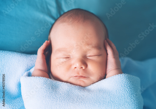 Newborn sleep at first days of life. Portrait of new born baby one week old in crib in cloth background.