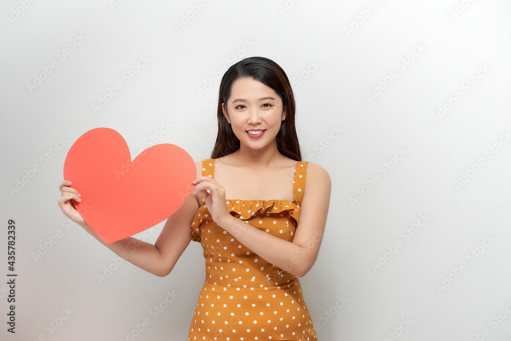 smiling pretty woman looking upwards, holding large red heart to chest daydreaming of men in love, smiling pretty woman looking upwards, holding large red heart to chest daydreaming of men in love,