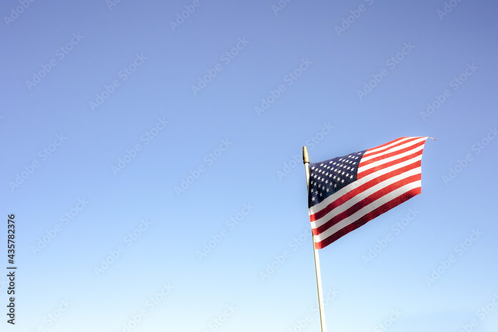 Flag on a blue sky background with copy space. American folag, simvon holiday concept.
