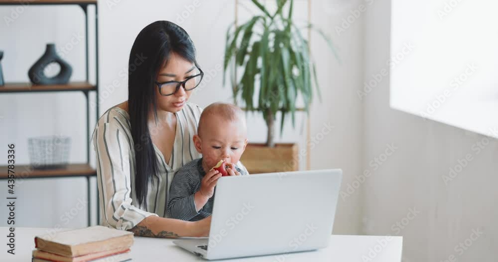 Young mother freelancer with her child working at home office using laptop Young mother freelancer with her child working at home office using laptop