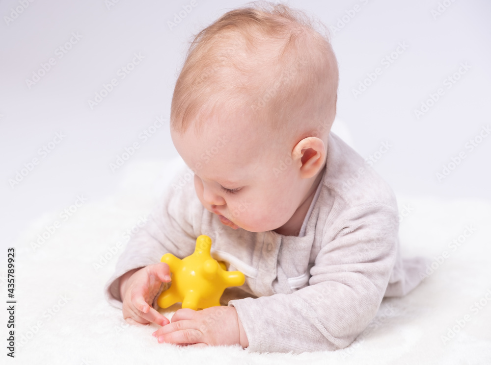 Pretty baby plays on the floor with a toy, white background Pretty baby plays on the floor with a toy, white background