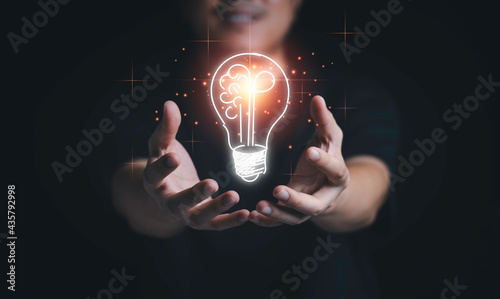 Man hand holding hanging glowing drawing light bulb with orange rays , creative thinking idea and innovation concept.
