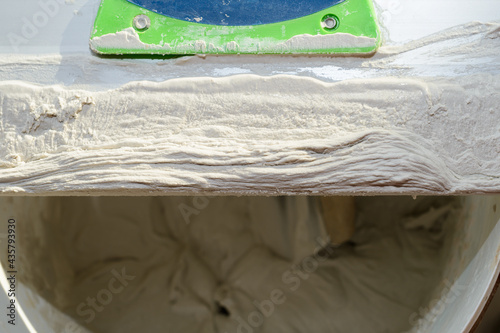Gypsum plaster on a long steel spatula on a bucket