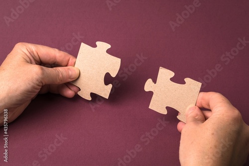 Close-up of a man's hand connecting a puzzle on a purple background. Business solutions, success and strategy concept