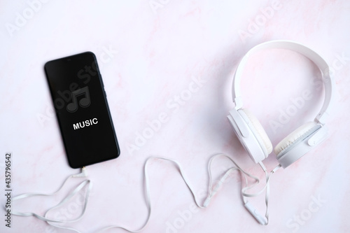 Smartphone with headphones connect on white background, listening to music concepts