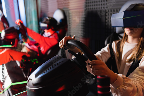 friends in vr headsets playing racing game on car simulators, blurred foreground