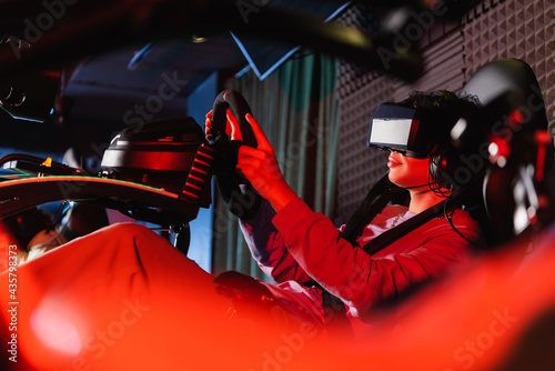 teenager in vr headset gaming on car racing simulator on blurred foreground