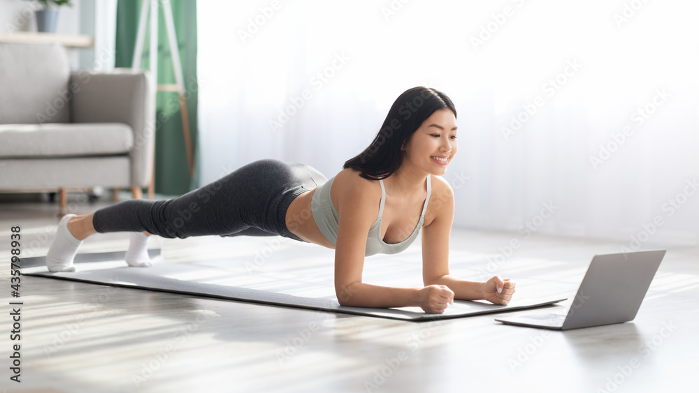 Fit Asian Woman Training At Home With Laptop, Making Plank Exercise Fit Asian Woman Training At Home With Laptop, Making Plank Exercise