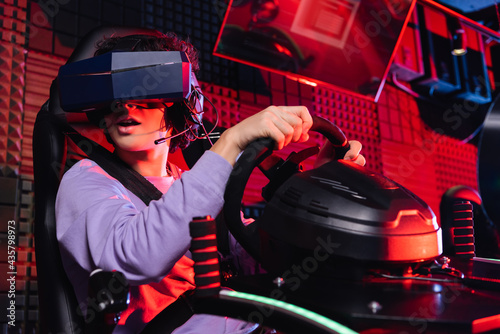 amazed teenager gaming on car racing simulator in vr headset photo