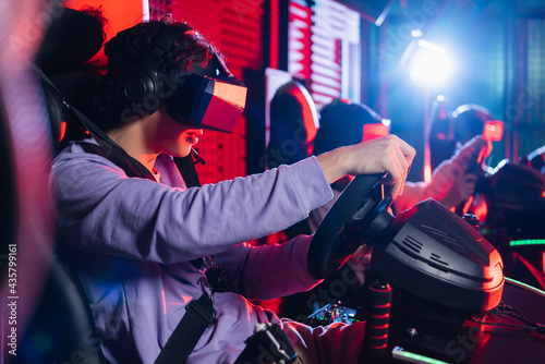 teenage boy in vr headset playing racing game on car simulator photo