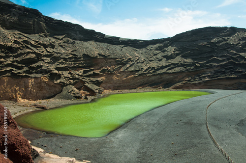 Beautiful green lake with large rocks in El Golfo Spain under a blue sky photo