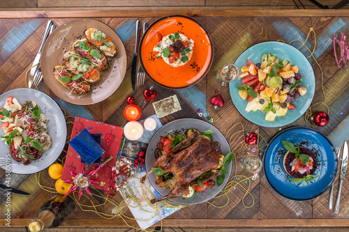 Flat lay of delicious Christmas themed dinner table with roasted duck, appetizers and salads