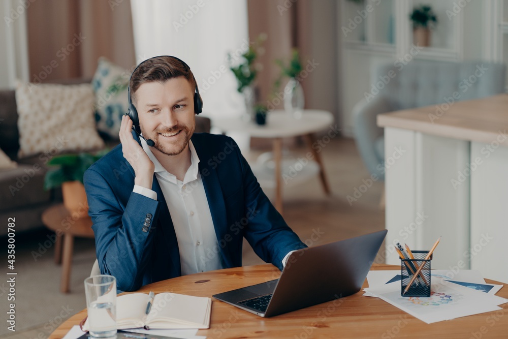 Smiling handsome young businessman in headset studying online at home Smiling handsome young businessman in headset studying online at home