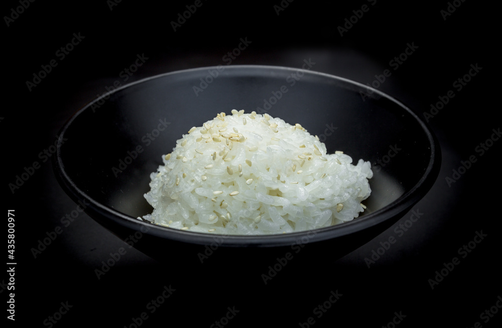 Japanese rice topped with white sesame on black bowl. Japanese rice topped with white sesame on black bowl.