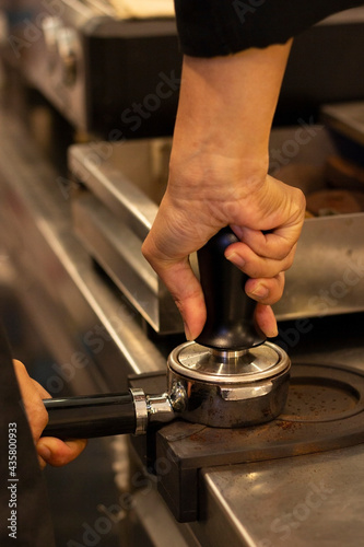 The hand is grinding the coffee beans with a grinder. Barista making coffee by machine. counter of coffee shop.