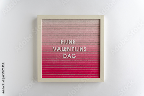Pink Board Words That Spell Fijne Valentijn's Dag (translation: Happy Valentine's Day), on a white background, horizontal photo