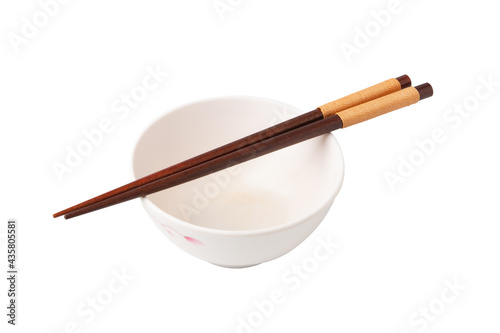 Small white bowl is empty, and chopsticks are placed on top of the bowl isolated on a white background.
