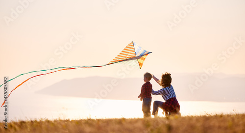 Happy family  mother and son  launch  kite on nature at sunset photo
