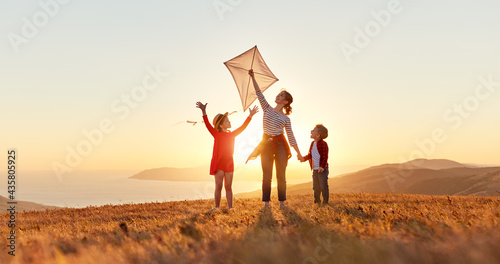 Happy family  mother and kids  launch  kite on nature at sunset #435805925