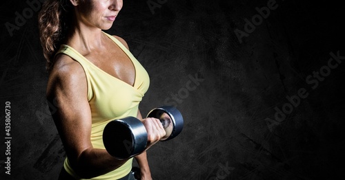 Composition of midsection of strong caucasian woman lifting dumbbells