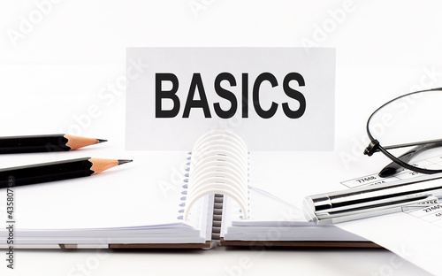 Text BASICS on paper card,pen, pencils,glasses,financial documentation on table - business concept
