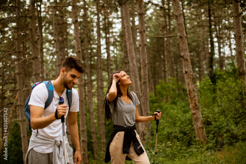 Smiling young couple walking with backpacks in the forest
