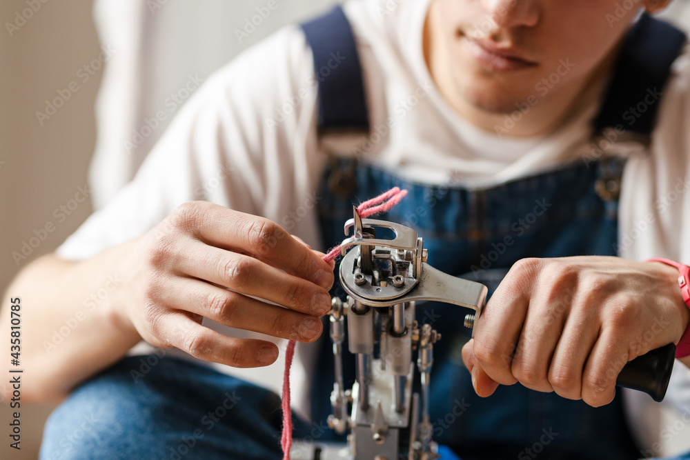 Young white man working with sewing machine indoors
