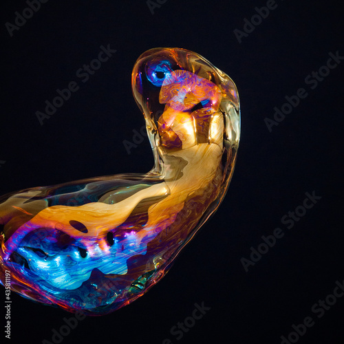 Amorphous and colorful isolated soap bubble with black background.