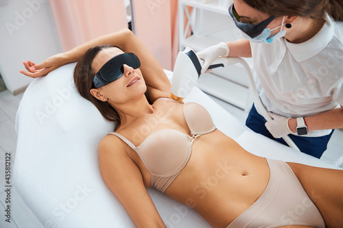 Woman in safety goggles smiling during a non-invasive medical procedure