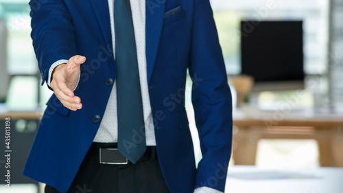 Cheerful Asian businessman reaching out hand for handshake