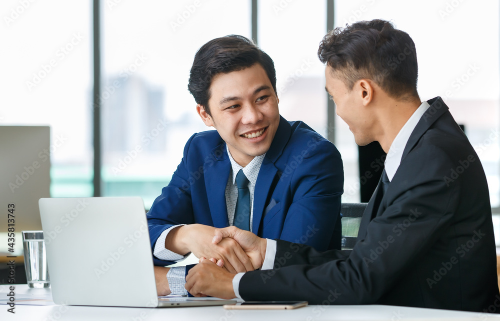 Cheerful Asian businessmen shaking hands in office