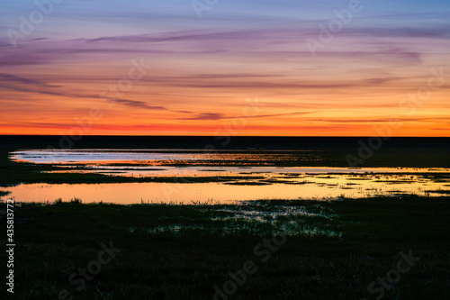 Sunset over the grassland between the dike and the wetlands.