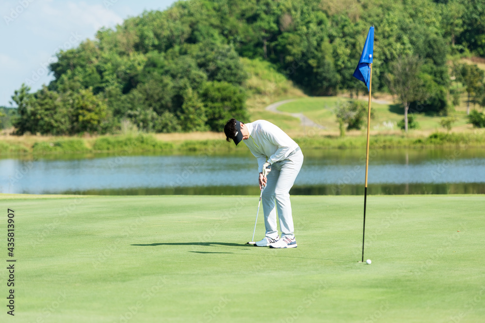 Golfer man playing golf aiming shot for putting ball on the hole with club on green course.  Professional people hobby in holiday and vacations in sunny morning day on club golf