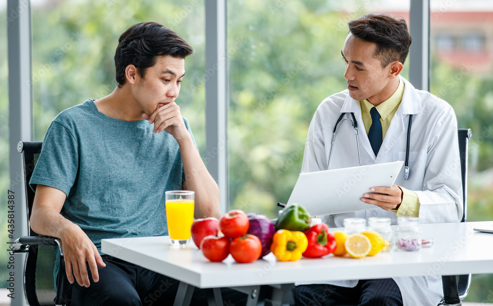 Friendly Asian nutritionist showing table to patient Friendly Asian nutritionist showing table to patient